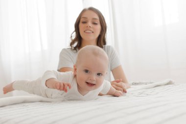 Anne ve bebek oynama ve yatağa gülümseyen