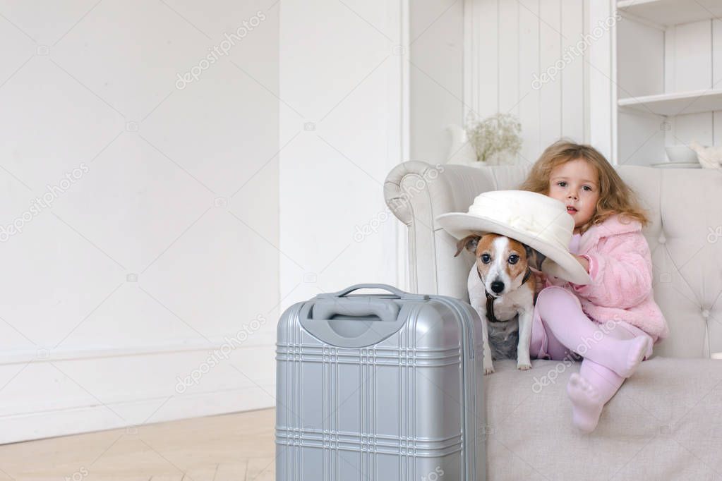 A little girl with suitcases and a dog in interior
