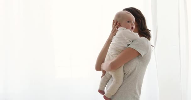 Mãe segura um bebê no fundo da janela dos braços — Vídeo de Stock