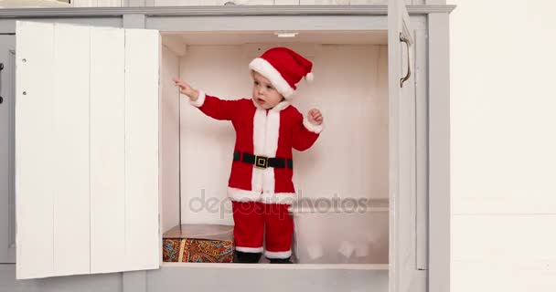 Baby boy in a Santa suit opens closet from inside — Stock Video