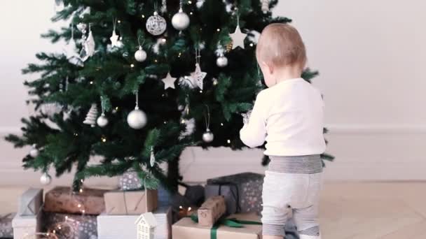 Малыш смотрит на игрушки на елке — стоковое видео