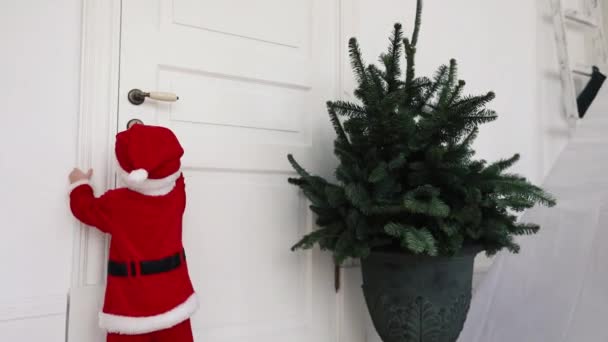 Little child in santa suit try to open door home — Stock Video