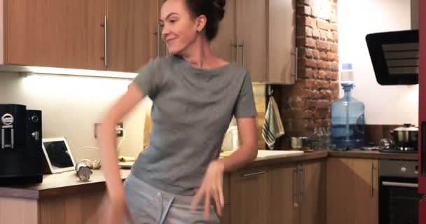Счастливая женщина на кухне поет и танцует — стоковое видео