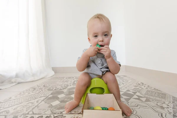 Baby sitter på pottan och äta grönsaker — Stockfoto