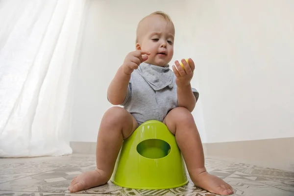 Baby sitter på pottan och äta grönsaker — Stockfoto