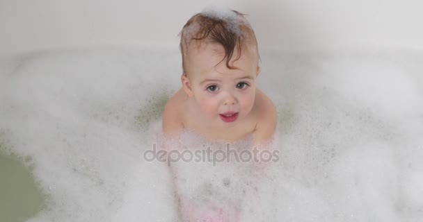 Μωρό ψάχνει προς τα πάνω σε μια μπανιέρα γεμάτη από αφρώδες υλικό — Αρχείο Βίντεο
