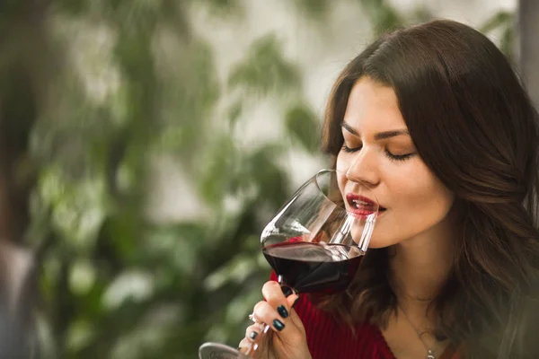 Um gole de vinho tinto de uma menina bonita — Fotografia de Stock