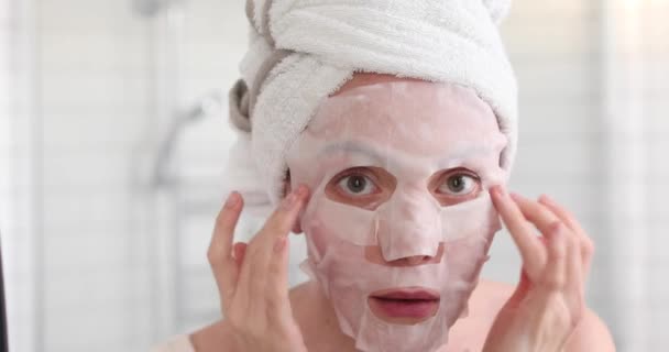 Κορίτσι εφαρμόζοντας μάσκα στο πρόσωπό της ψάχνουν στον καθρέφτη — Αρχείο Βίντεο