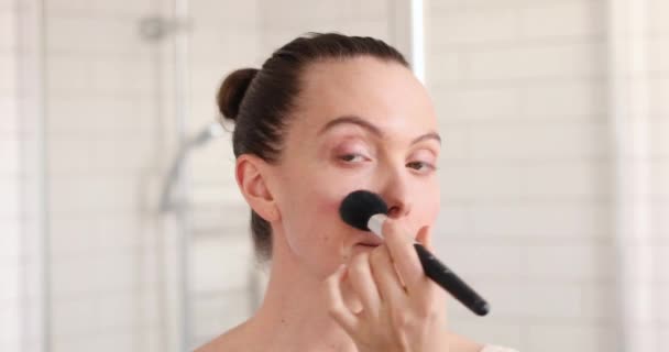 Женщина наносит косметику большой кистью — стоковое видео