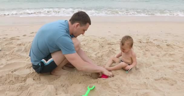 Człowiek z niemowlęciem w piasku — Wideo stockowe