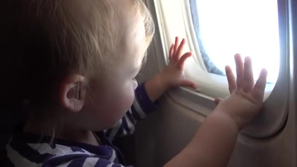 Ребенок смотрит через иллюминатор в самолете — стоковое видео