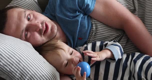 Pai e criança deitados na cama de manhã closeup — Vídeo de Stock