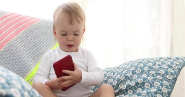 Ребенок с помощью смартфона сидит в кресле один — стоковое видео