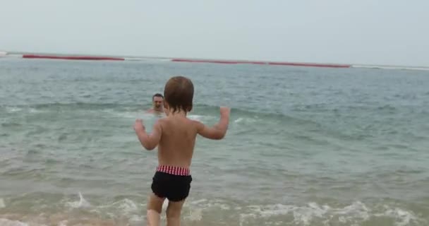 Μικρό βρέφος τρέχει με άνθρωπος στη θάλασσα — Αρχείο Βίντεο