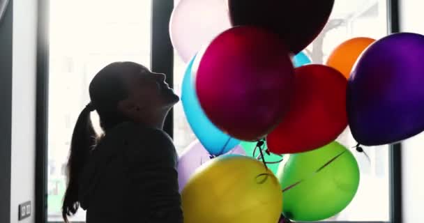 Woman enjoys balloons in front window silhouette — Stock Video