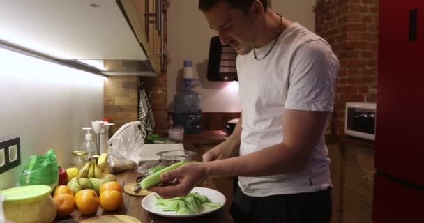 Joven hombre picando verduras en la cocina — Vídeos de Stock