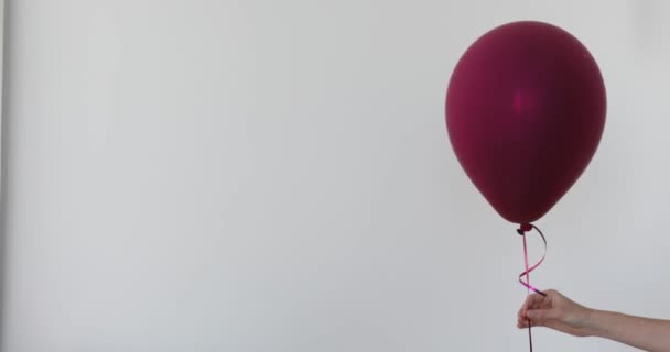 Frauenhand hält lila Ballon weißen Hintergrund — Stockvideo