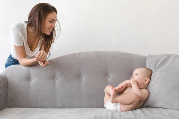 Содержание женщины с ребенком на сером диване — стоковое фото