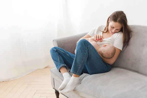 Счастливая женщина обнимается с младенцем на диване — стоковое фото
