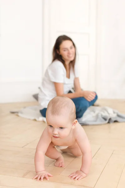 Donna guardando bambino strisciare sul pavimento — Foto Stock