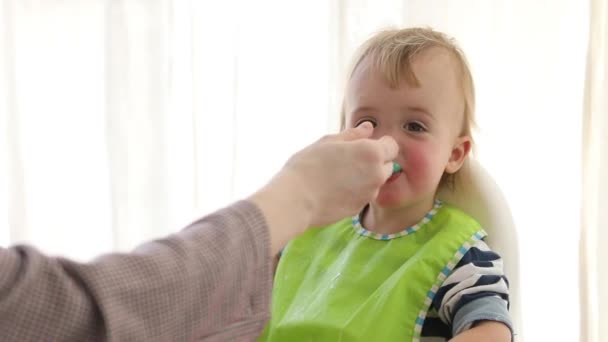 Mother feeding baby with spoon indoors — Stock Video