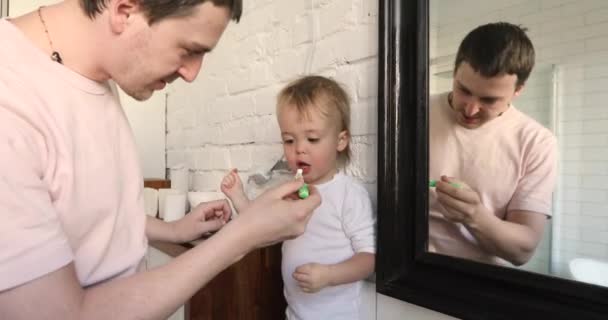 Tata jest szczotkowanie zębów próchnica do jego syn łazienka — Wideo stockowe