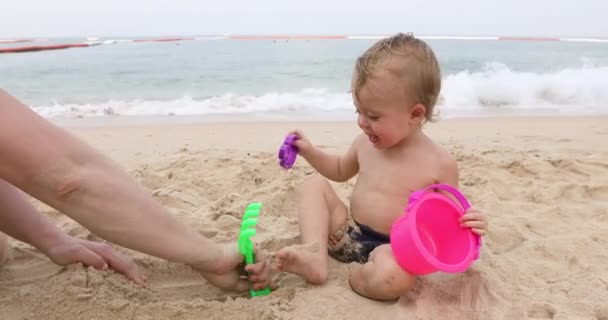 Мужчина играет с младенцем на песке — стоковое видео