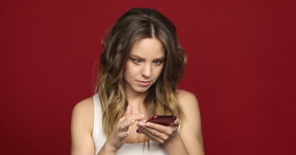 Menina bonita olha para o telefone celular chocado de perto — Vídeo de Stock