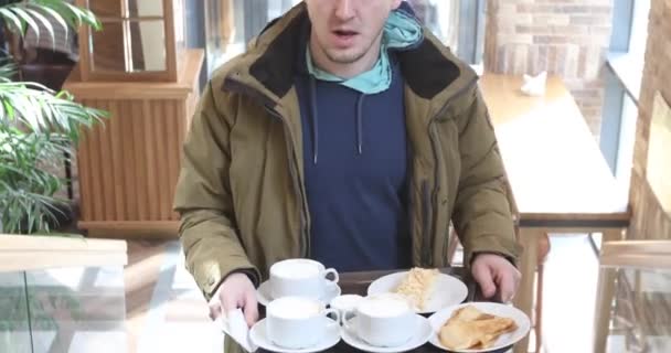 Mannen bär bricka med sin frukost i caféet — Stockvideo