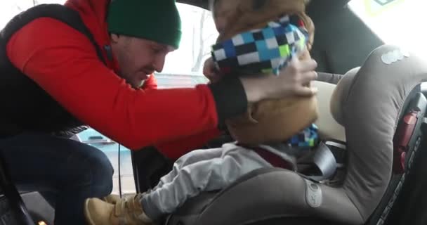Vader zet baby in beschermende stoel vastmaakt banden — Stockvideo
