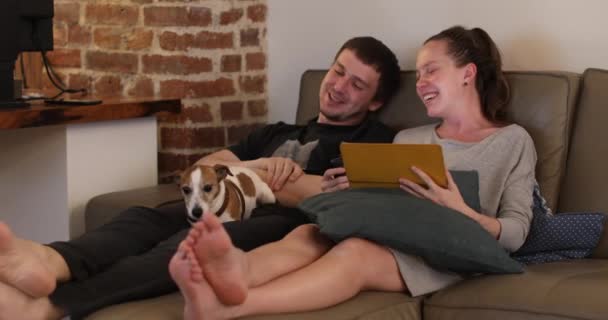 Mladý pár se psem chatování při sezení pohovka — Stock video