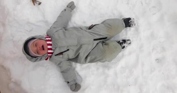 Chico llorón haciendo ángel de nieve en la calle — Vídeos de Stock