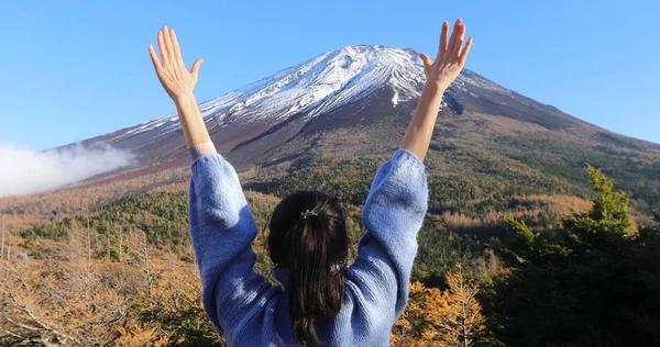 Woman raising hands greeting snowy mountain