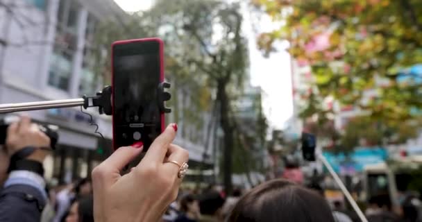 Disparos de persona en el teléfono inteligente en palo selfie en la calle — Vídeos de Stock