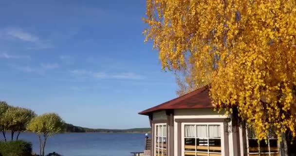 Fehér ház a tengerparton közel a víz alatt ősz fa — Stock videók