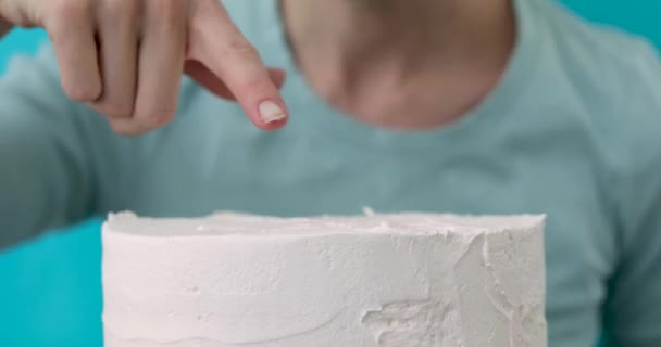 Kvinna kör ett finger på en kaka och slickar en grädde — Stockvideo