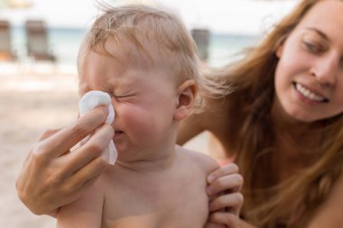 Mother helping baby to blow nose
