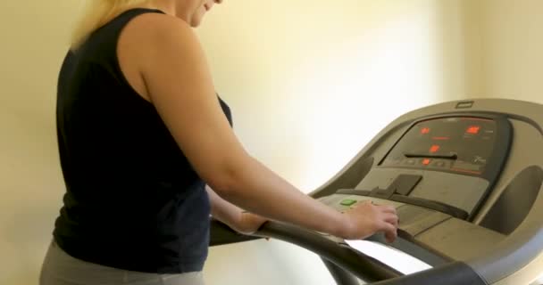 Névtelen, kövér nő a sportruházatban, otthon futópadon dolgozik. — Stock videók