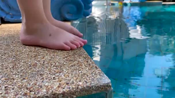 Child touching water in swimming pool by leg — Stock video