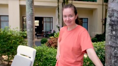 Gülümseyen kadın otel bahçesinde duruyor.