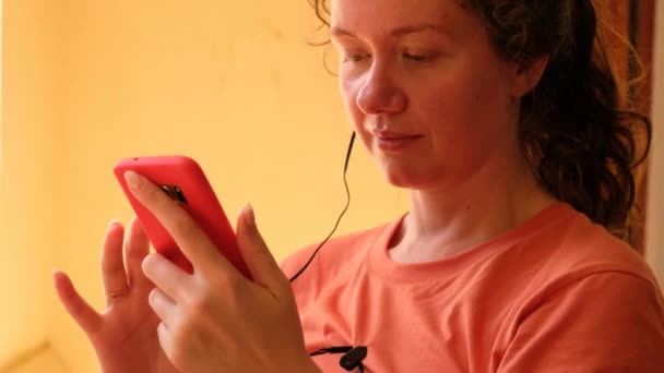 Задоволена молода жінка використовує смартфон вдома — стокове відео