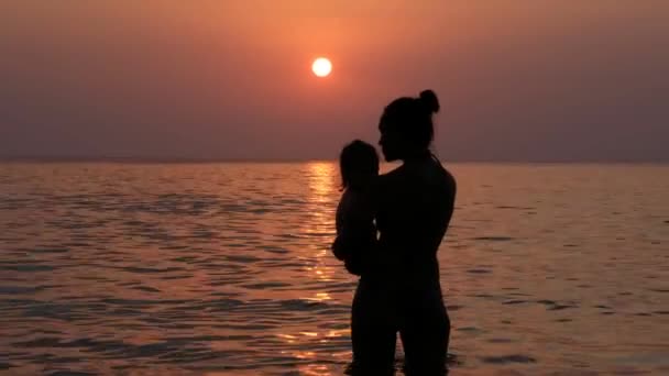 Mujer con niño en el mar durante la hermosa puesta del sol — Vídeos de Stock