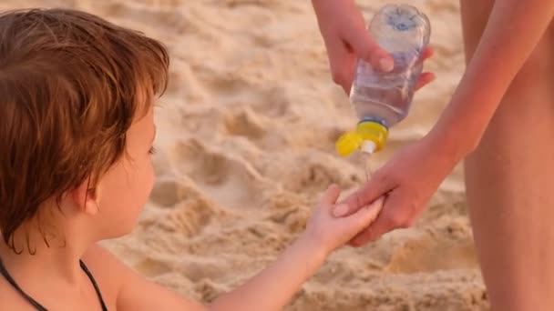 Anne plajda çocuğun elini yıkıyor. — Stok video