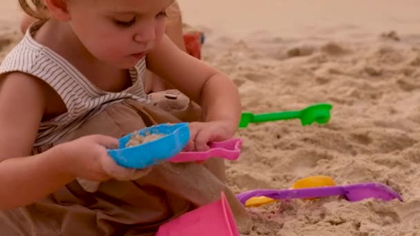 Dziewczynka bawiąca się piaskiem na plaży — Wideo stockowe