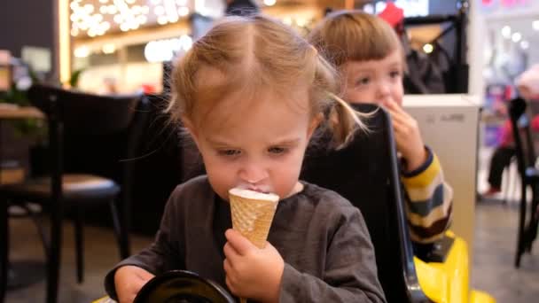 Menina dirigindo carro de brinquedo e comer sorvete — Vídeo de Stock