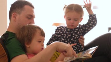 Father reading book to kids on sofa