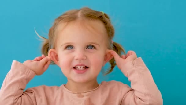 Hermosa niña en el estudio señala sus oídos — Vídeos de Stock