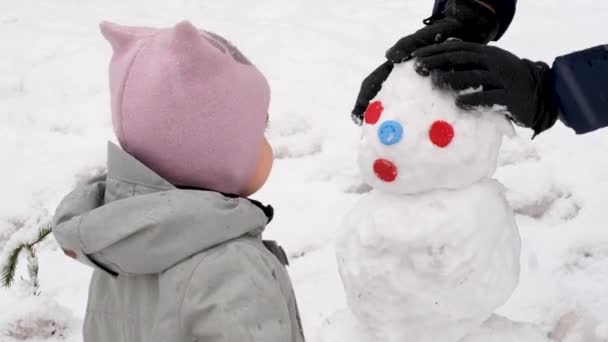 Enfant avec bonhomme de neige dans la rue d'hiver — Video