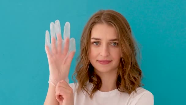 Молодая женщина надевает латексную перчатку — стоковое видео