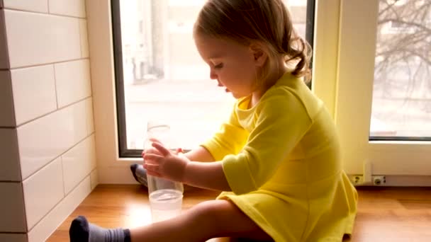 Спокійна маленька дівчинка з пляшкою води вдома — стокове відео